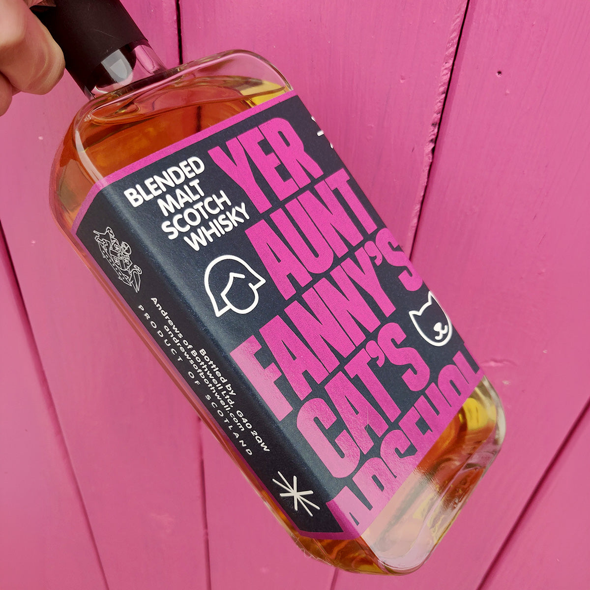 Bottle of Yer Aunt Fanny's held against a bright pink painted door