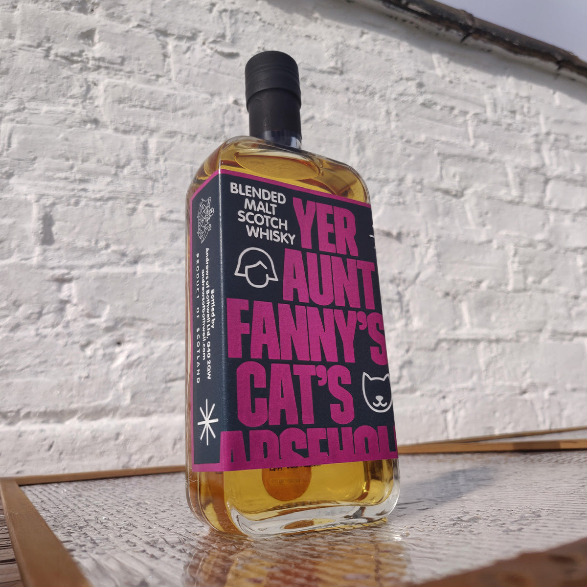 Yer Aunt Fanny's blended malt Scotch whisky in sunlight against a white brick wall